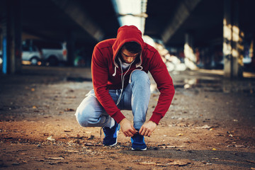 Handsome young man man tying sneakers and prepares for jogging