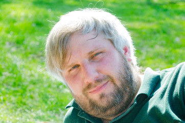 Portrait Adult man with gray hair and beard smiling close-up on a background of green nature