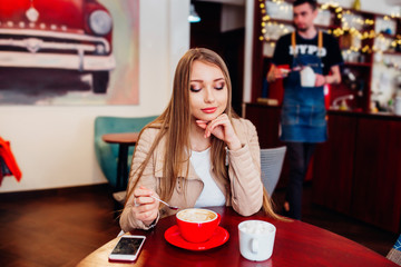 Portrait of young gorgeous female drinking coffee and looking with smile out of the coffee shop window while enjoying her leisure time, nice business woman lunch in modern cafe during her work break