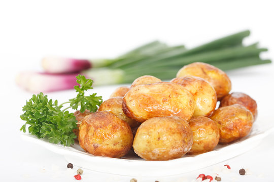 Young roasted potatoes with parsley and spring onions on white background