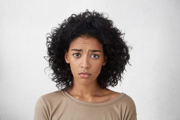 Headshot of regretful young mixed race woman feeling sorry for doing something wrong, looking at...