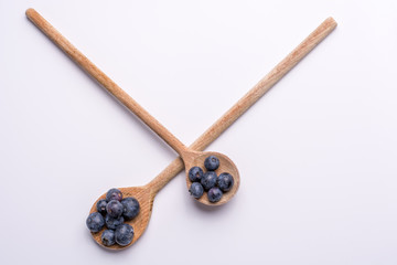 Blueberries on wooden spoons on white background