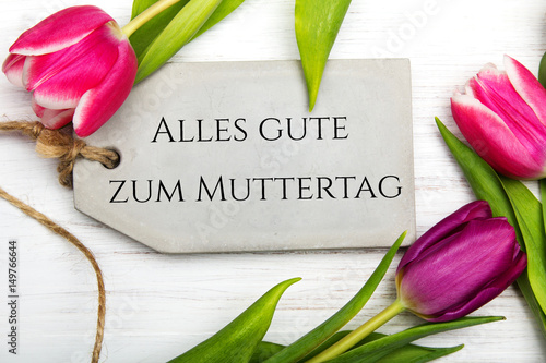 German Mother's day card with word Muttertag (Mother's day) tulip and hearts on white wooden background.
