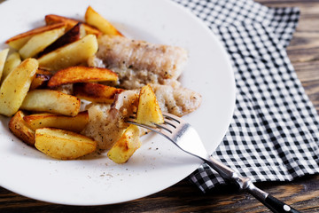 Delicious dinner, fast food, a national dish, fish with fried potatoes, fish and chips, sauce and white toast bread on a dark wooden background 