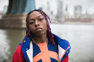 A candid portrait of an attractive, young, black woman sitting on the shore of New york City's East...