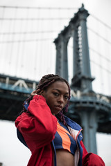 A candid portrait of an attractive, young, black woman sitting on the shore of New york City's East...