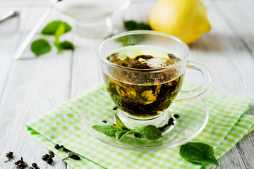 Drinks, green leaf tea with sugar, mint and lemon on a white rustic wooden background 
