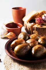 Russian and Ukrainian national cuisine, potatoes in their skin with fish, white bread, onions, garlic, cucumber and vegetable oil on a light wooden background 