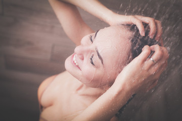 Young beautyful woman under shower in bathroom