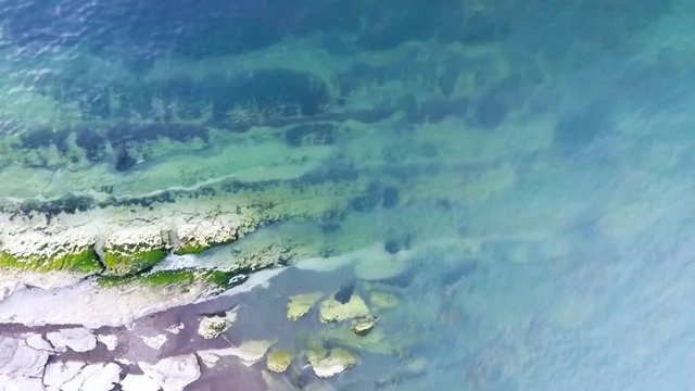 Aerial birds eye view looking down at sea waves crashing down. Green and blue sea top view drone drone footage  