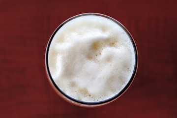 Glass of beer foam over wooden table
