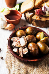 Russian and Ukrainian national cuisine, potatoes in their skin with fish, white bread, onions, garlic, cucumber and vegetable oil on a light wooden background 