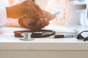 Concept of doctor working and playing smartphone on the desk.