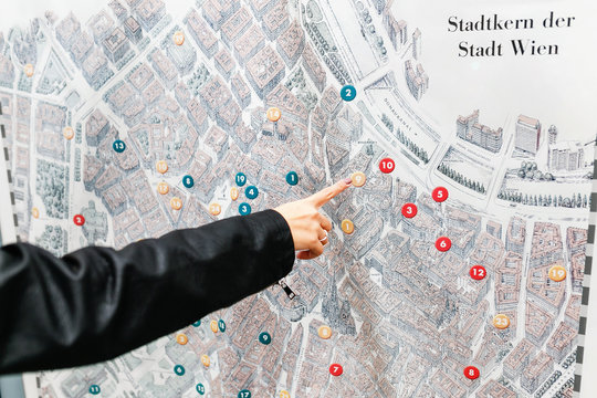 Detail of young woman tourist hand pointing at street city map