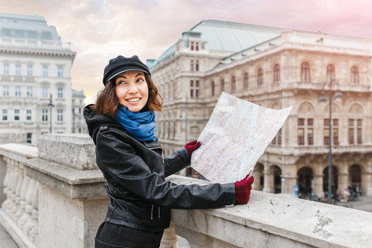 Young brunette eastern or asian woman using city map in Vienna center street