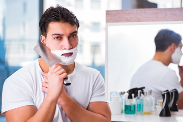 Young handsome man shaving in the morning