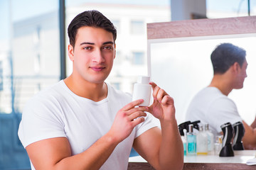 Young handsome man applying face cream