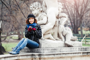 Young brunette traveler woman talking and using cell phone in the garden, roaming and phone connection abroad concept