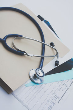 Afile folder, a stethoscope and a pen on ekg