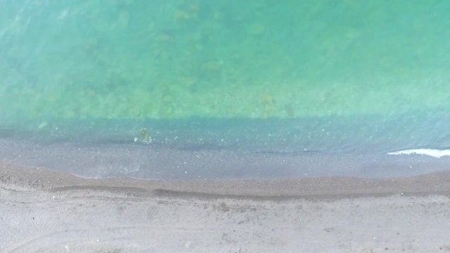Aerial birds eye view looking down at sea waves crashing down. Green and blue sea top view drone drone footage  