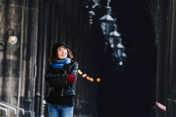 A woman in a leather jacket posing in a Gothic old corridor