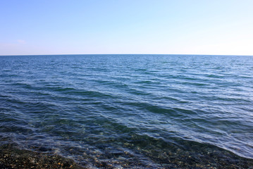 Naklejka na ściany i meble Stony shore of serene blue sea.