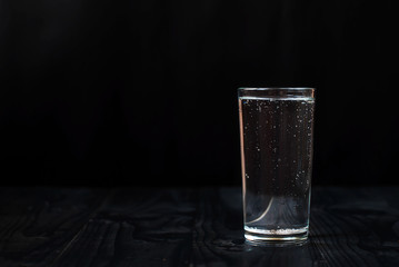 Juste un verre d& 39 eau sur fond noir. Eau minérale dans un verre sur une table en bois sombre.