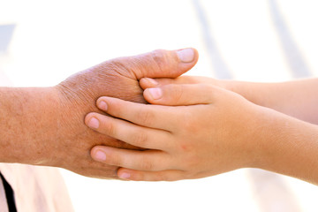 Hands of young child and old senior