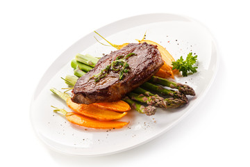 Grilled beefsteak with asparagus and carrot on white background 