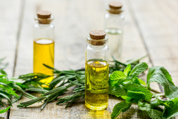 herbal extract in glass bottles, mint and rosemary for spa on wooden table background