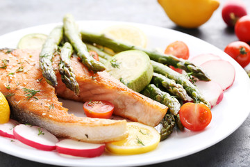 Steak of salmon with asparagus and vegetables on grey wooden table