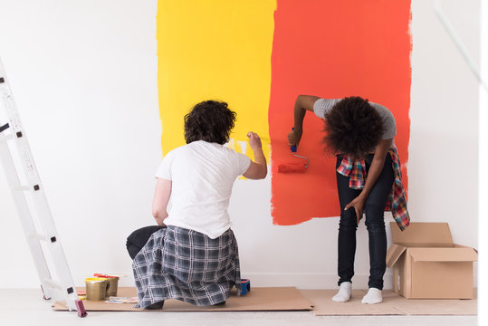 multiethnic couple painting interior wall