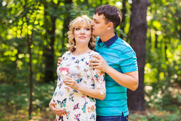 Happy young pregnant couple hugging in nature