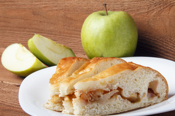 Homemade apple cake and green apple over natural wood background