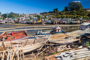 Fototapeta na wymiar Fishing boats and palafitos (stilt houses) during low tide in Castro, Chiloe island, Chile