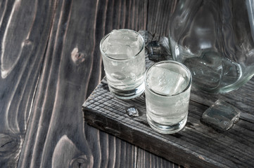 Two shot glasses with cold vodka on wooden table, selective focus