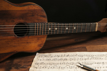 Fototapeta na wymiar Ancient little acoustic guitar and hand-written notes on the table