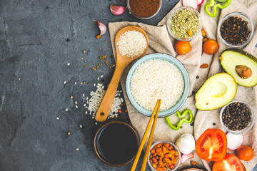 Rice, Spices and Vegetables over dark rustic background. Vegetarian cooking concept. Asian or Indian food