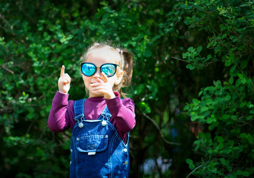 Ребенок в очках и  в сарафане из каттона. Маленькая модель. Модное. Девочка позирует на открытом воздухе  в парке