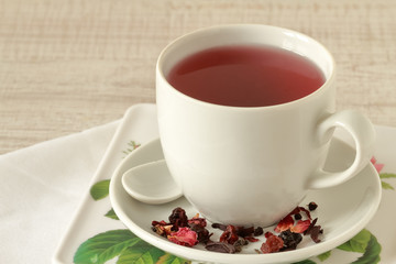 A cup of tea with petals, dry berries and fruits