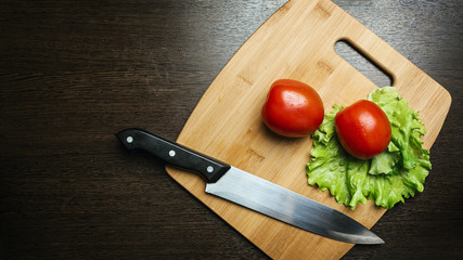 tomato and a kitchen knife on a cutting board