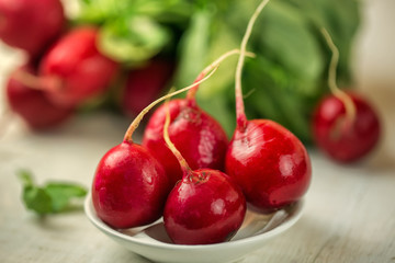 Red radishes in bowl on wooden table. Vegetable of cabbage family. 