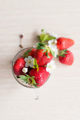 Fresh strawberries in Cup on light background with flowers and leaves