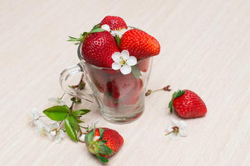 Fresh strawberries in Cup on light background with flowers and leaves