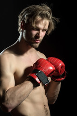Fototapeta na wymiar Attractive sexy boxer. Naked man in boxing red gloves in training. Beautiful boxer with fashionable hair and beard. Model for advertising sports, coach or gym