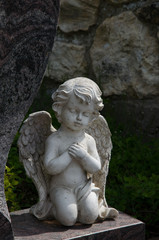 Fototapeta na wymiar knieende engelsfigur an einem grabstein