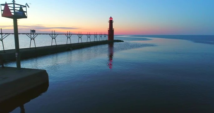 Scenic aerial flyby of Lake Michigan lighthouse and harbor at twilight, Algoma, Wisconsin