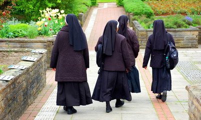 Nonnen in Ordenstracht laufen durch Kräutergarten