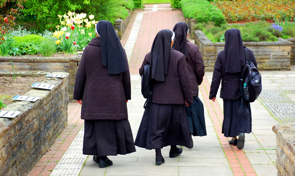 Nonnen in Ordenstracht laufen durch Kr&auml;utergarten