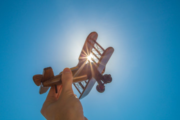 The hand with a wood plane on the background of the bright sun